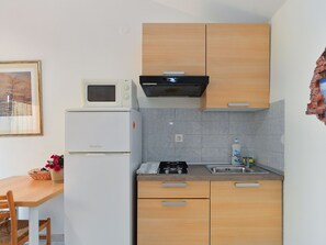 Een koelkast, een magnetron, kookgerei, borden en bestek