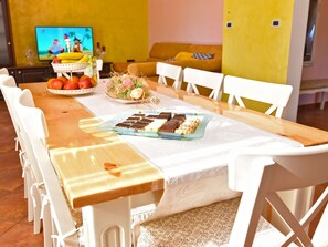A dining table with chairs, a fruit bowl, a vase with flowers, and a plate of desserts. - Apartment 1561 by Interhome (Cere)