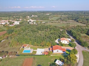An aerial view of a residential area with houses, a swimming pool, and a road. - Apartment 1561 by Interhome (Cere)