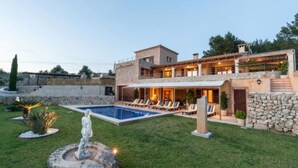 Une maison moderne à deux étages dotée d’une piscine, d’un espace salon extérieur et d’une fontaine.