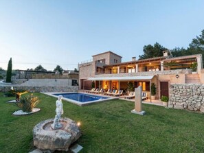 Ein modernes, zweistöckiges Haus mit Swimmingpool, Sitzgelegenheiten im Freien und einer Fontäne.