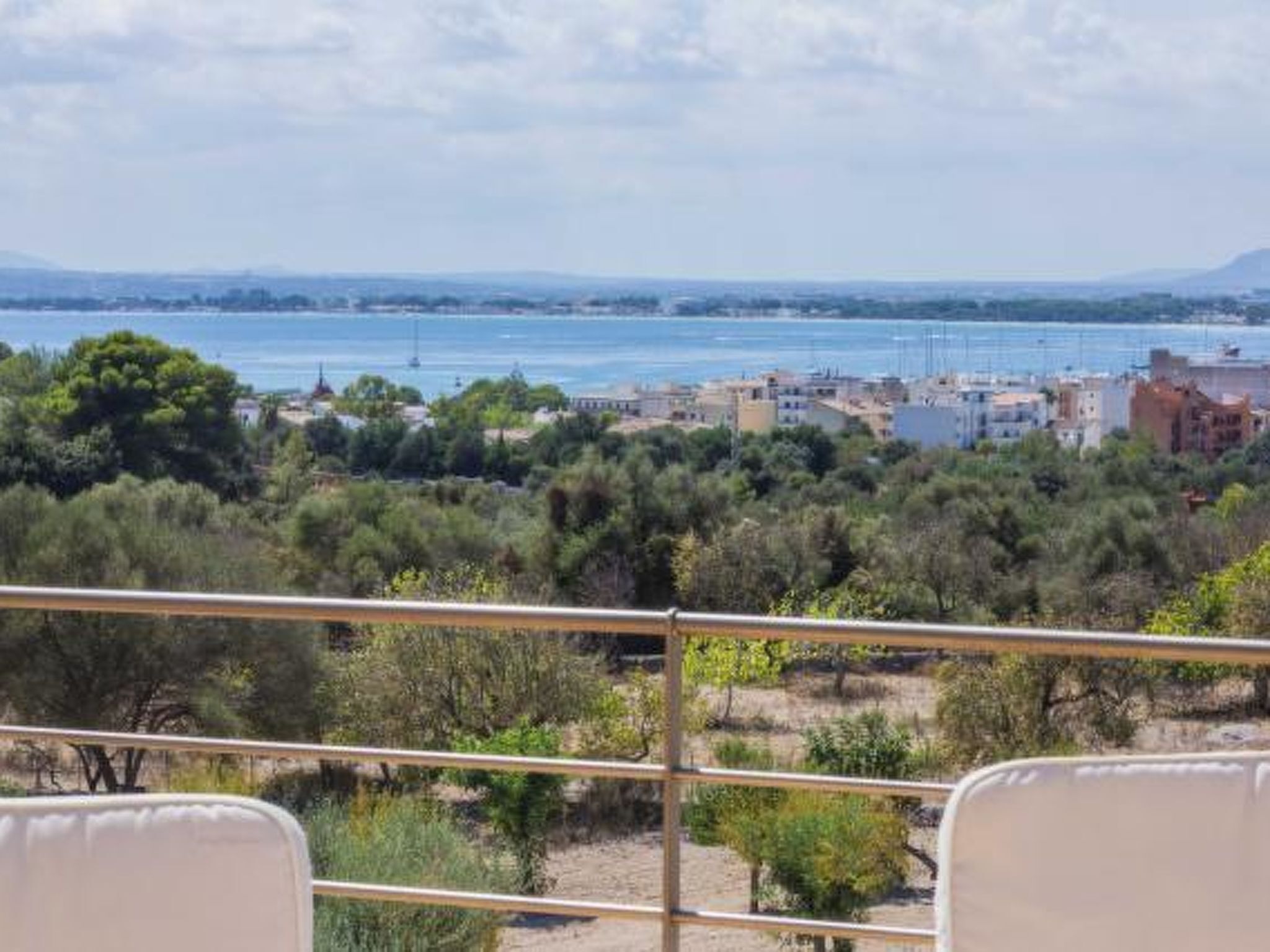 Uma varanda com vista para uma cidade costeira, vegetação e edifícios.