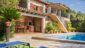 Uma villa de dois andares com piscina, área de estar externa e escadaria que leva ao andar superior.