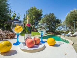Ein Poolbereich mit einer Champagnerflasche, Gläsern und Früchten auf einem Tisch.