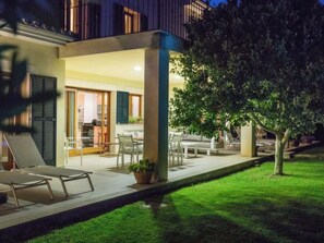 Eine moderne Außenpatio mit Sitzgelegenheiten, einem Baum und einem Hauseingang.