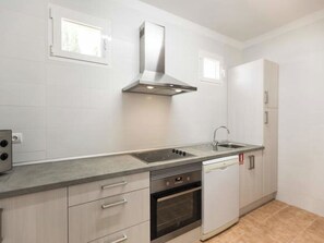 Eine moderne Küche mit Dunstabzugshaube aus Edelstahl, Backofen, Geschirrspüler und Spüle.