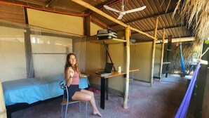 Een eenpersoonskamer met een bed, een bureau met een laptop en een stoel.