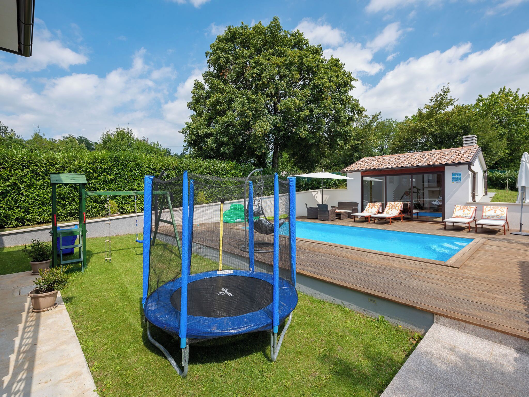 Un jardin avec un trampoline, une piscine et du mobilier d’extérieur.