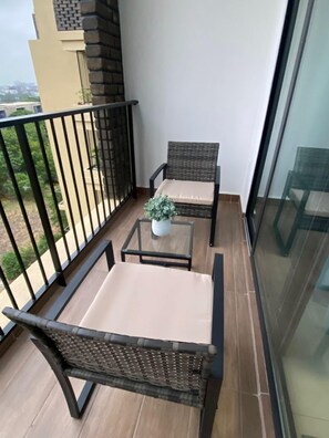 Ein Balkon mit zwei Korbstühlen, einem kleinen Tisch und einem Blumentopf.