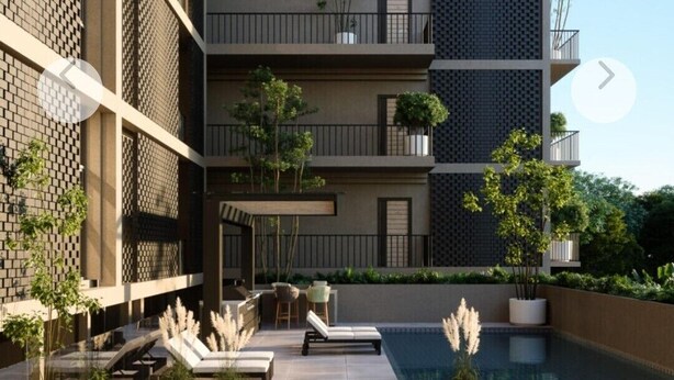 Un edificio moderno con varios balcones, piscina y zonas de estar al aire libre.