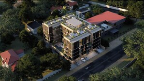 Un edificio moderno de varios pisos con jardines en la azotea, un área de estacionamiento y vista a la calle.