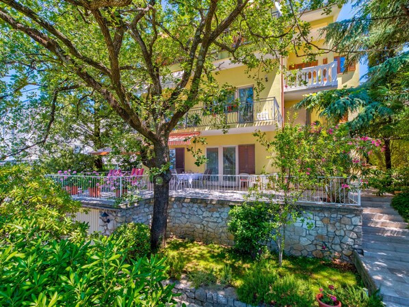 A multi-story building with balconies, stone walls, and lush greenery. - Irena Apartments 2 kat / HR-10649-02 by Interhome (Selce)