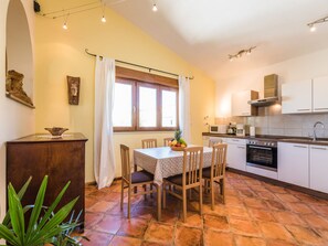 A compact kitchen with a dining area, a window with curtains, and a tiled floor. - Irena Apartments 2 kat / HR-10649-02 by Interhome (Selce)