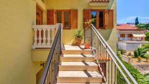 A staircase leading to a balcony with a railing, a potted plant, and a view of neighboring buildings. - Irena Apartments 2 kat / HR-10649-02 by Interhome (Selce)