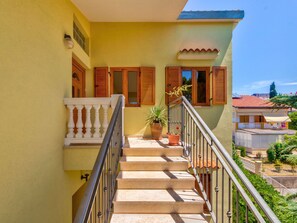 A staircase leading to a balcony with a railing, a potted plant, and a view of neighboring buildings. - Irena Apartments 2 kat / HR-10649-02 by Interhome (Selce)