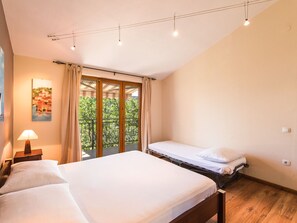 A bedroom with a large bed, a smaller bed, a nightstand with a lamp, and a painting on the wall. - Irena Apartments 2 kat / HR-10649-02 by Interhome (Selce)