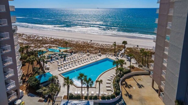 A hotel with a pool, beach view, and multiple balconies. - Dunes of Panama C104 (Panama City Beach)
