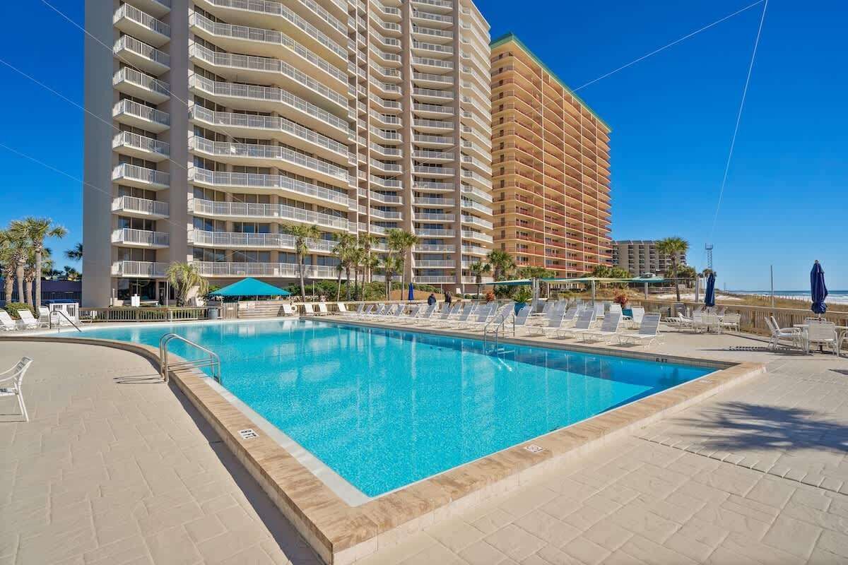 Una piscina amb gandules i un edifici alt al fons.