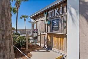 A wooden building with a sign reading "TIKI" and another sign indicating "HOURS 11-3 PM".