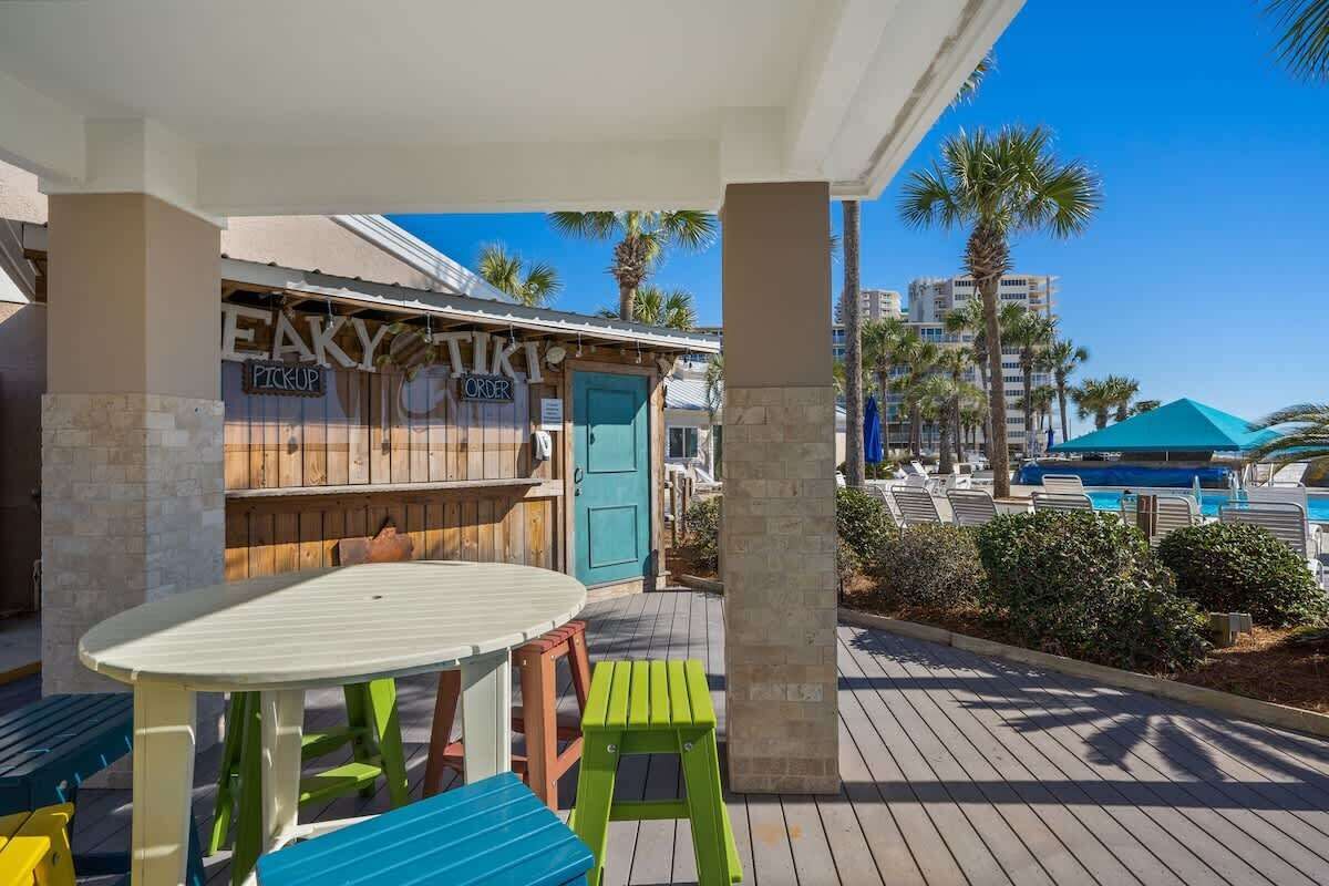 Ein Restaurant direkt am Strand mit Außenbereich, einem Pool und Palmen im Hintergrund.