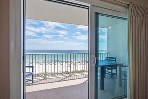 Ein Balkon mit Blick auf Strand und Meer, inklusive Tisch und Stühlen.
