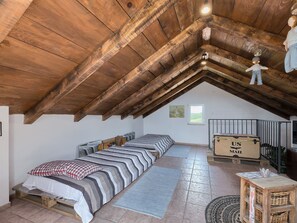 A loft-style bedroom with a sloped ceiling, a bed with striped bedding, a small table, and a window. - House Rea by Interhome (Buzet)