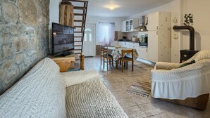 Een gezellige woonkamer met een stenen muur, een houten ladder, een televisie, een bank en een eethoek met stoelen en een tafel.