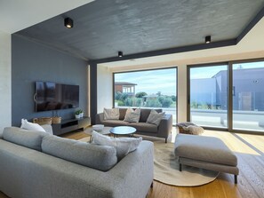 A modern living room with a grey sofa, a coffee table, and a TV mounted on the wall. - Villa Amella by Interhome (Barbariga)