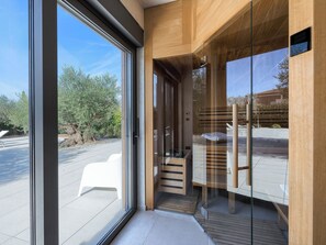 A modern interior with large glass doors, wooden paneling, and a view of the outside. - Villa Amella by Interhome (Barbariga)