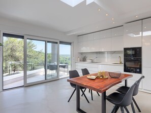 Een moderne keuken met witte kastjes, een houten eettafel en uitzicht op de omgeving.