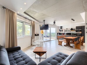 Een moderne woonkamer met een bank, een houten salontafel en een eethoek met tafel en stoelen.