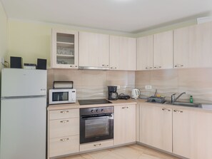 A kitchen with a refrigerator, microwave, toaster, coffee maker, kettle, sink, and cabinets. - House Horizon by Interhome (Pićan)