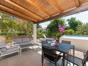 Eine Terrasse im Freien mit Holzboden, einem Pool und einer Sitzgruppe mit Tisch und Stühlen.