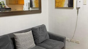 Un soggiorno moderno con un divano grigio, un grande specchio e opere d'arte astratte alle pareti.