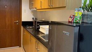 Una cucina moderna con mobili in legno, frigorifero in acciaio inossidabile e piano di lavoro nero.