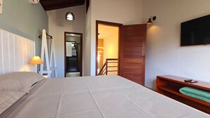 Ein Schlafzimmer mit einem Bett, einer hölzernen Bank, einem Fernseher und einer Treppe, die in einen anderen Raum führt.