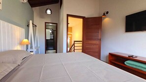 Ein Schlafzimmer mit einem Bett, einer hölzernen Bank, einem Fernseher und einer Treppe, die in einen anderen Raum führt.