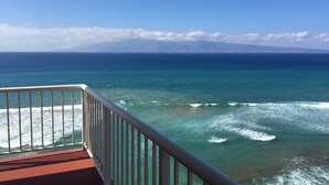 A balcony with a view of the ocean and a distant mountain.