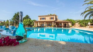 Ein Pool mit klarem, blauem Wasser, eine Spirituosenflasche und ein Haus im Hintergrund.