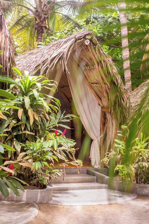 A thatched-roof structure with a staircase leading to it, surrounded by lush greenery and plants. - Bohemia Beach Tayrona (Santa Marta)