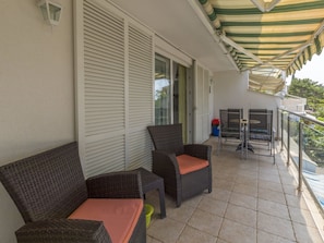 A balcony with wicker furniture, a table, and a chair. - KOTVICA / HR-10106-01 by Interhome (Selce)
