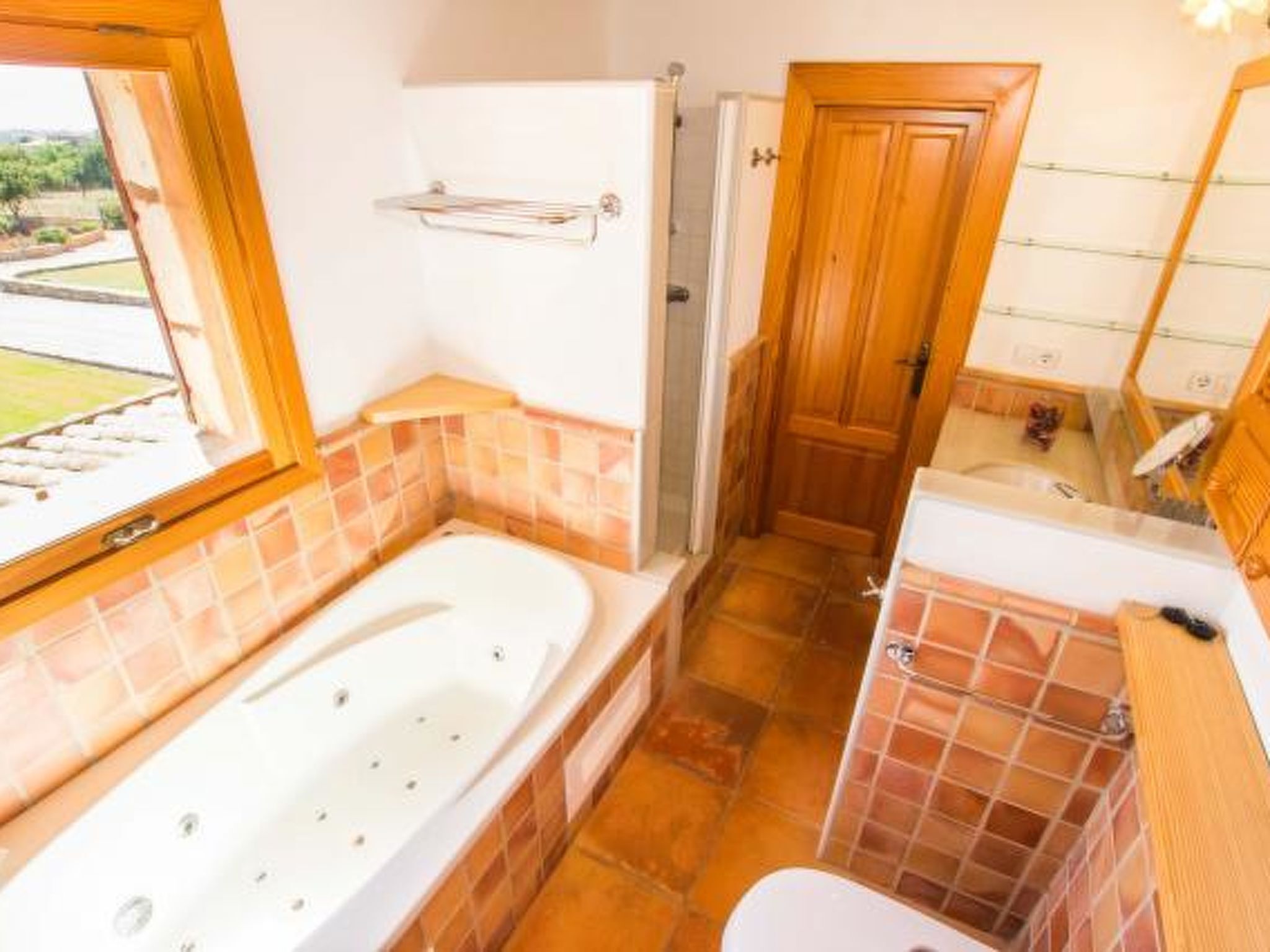 Un baño con bañera, inodoro y zona de ducha, que presenta puertas de madera y paredes con azulejos.
