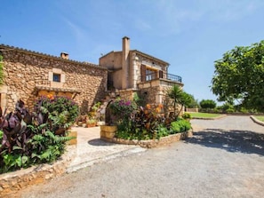 A stone building with a balcony, surrounded by well-maintained gardens. - Tovell 8 by Interhome (Sant Llorenç des Cardassar)