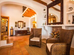 A room with wicker chairs, a fireplace, a mirror, and a staircase. - Tovell 8 by Interhome (Sant Llorenç des Cardassar)