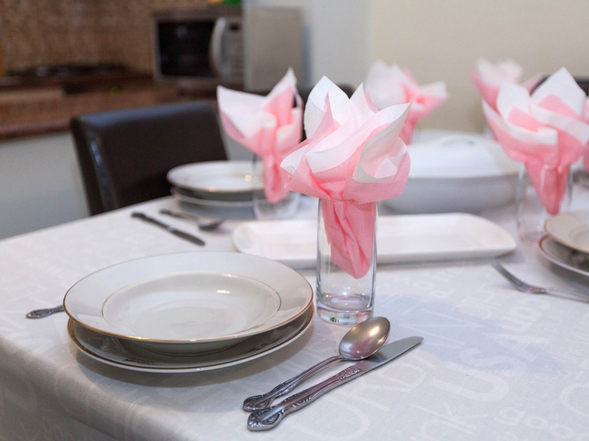 Une table dressée avec des assiettes, une cuillère et un verre décoré de motifs floraux roses.