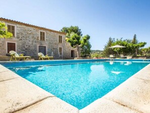 A stone building with a swimming pool, lounge chairs, and trees. - Manenta by Interhome (Manacor)