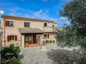A two-story building with a stone courtyard, potted plants, and a satellite dish. - Vacation home Cogol by Interhome (Manacor)
