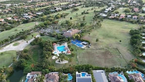 Eine Vogelperspektive auf einen Golfplatz mit Schwimmbad, Tennisplätzen und Wohnhäusern.