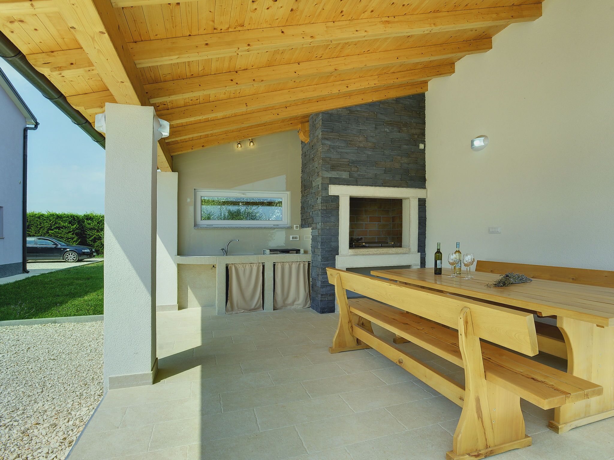 An outdoor kitchen area with a stone fireplace, wooden table, and bench.