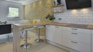 Una cucina moderna con parete a parete in pietra, un bancone in legno e TV integrata.